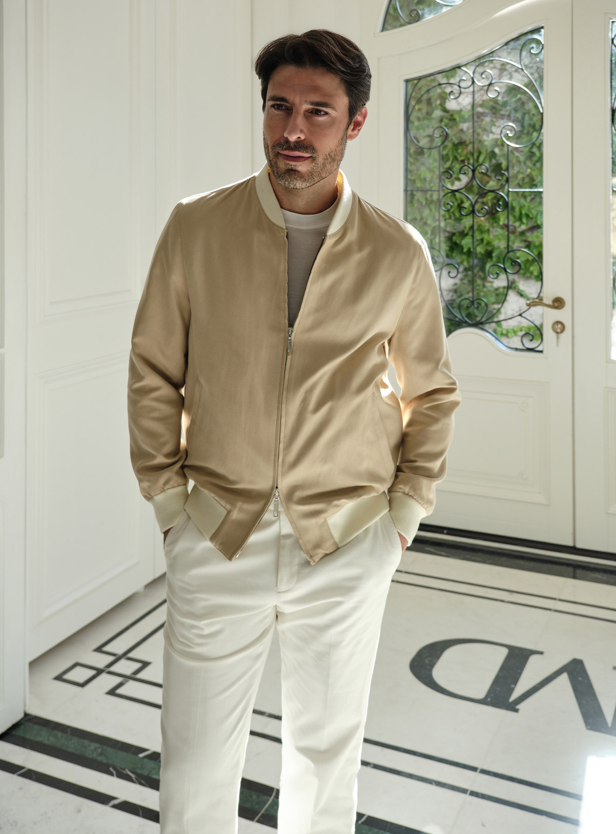 Beige Consiglieri zip bomber jacket worn with white trousers