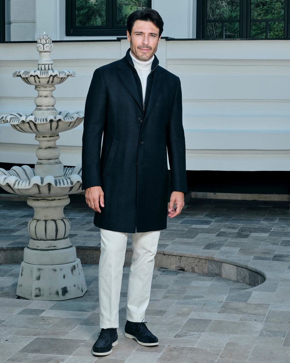 Black Consiglieri coat with a shirt collar, worn with white trousers