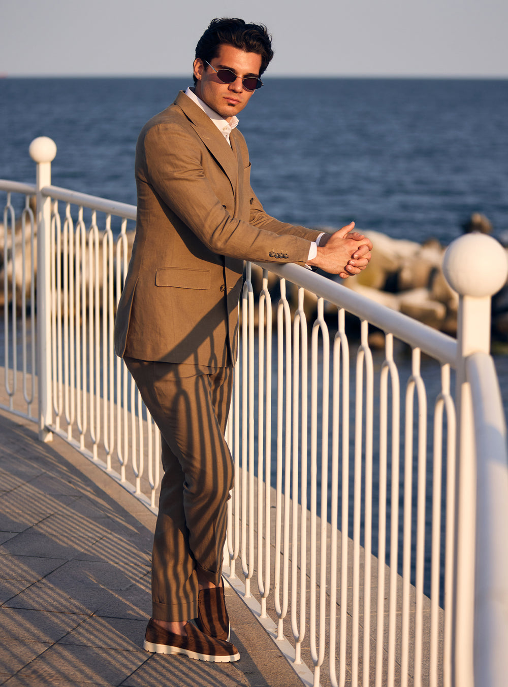 Brown double-breasted Consiglieri suit worn with an open-neck white shirt