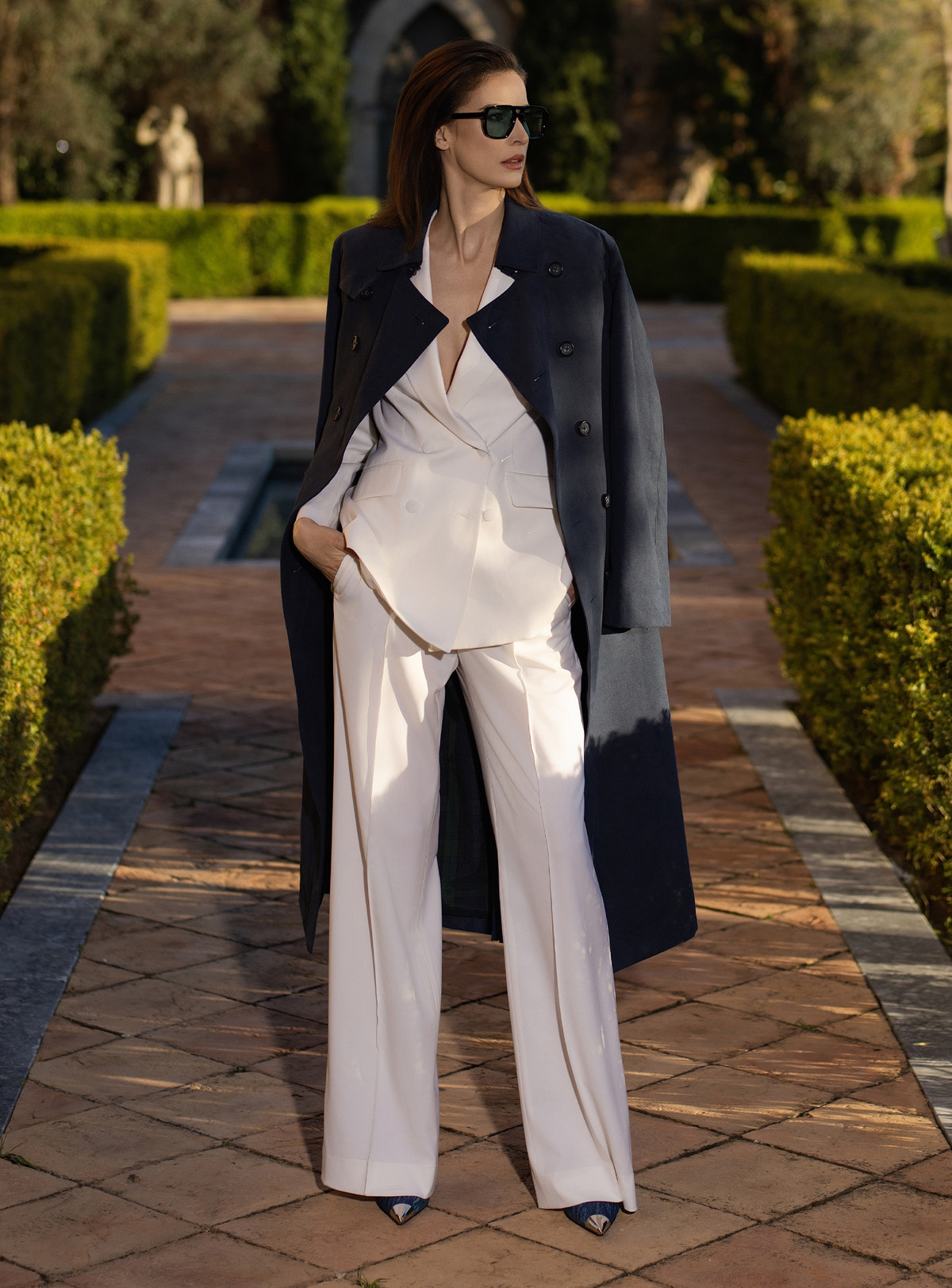 Navy Consiglieri DONNA trench coat draped over an ivory suit with wide-leg trousers