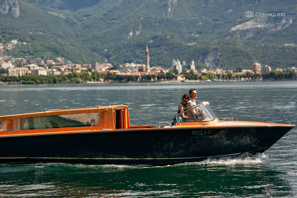 Wooden boat on a lake surrounded by mountains in the Consiglieri Sprezzatura campaign