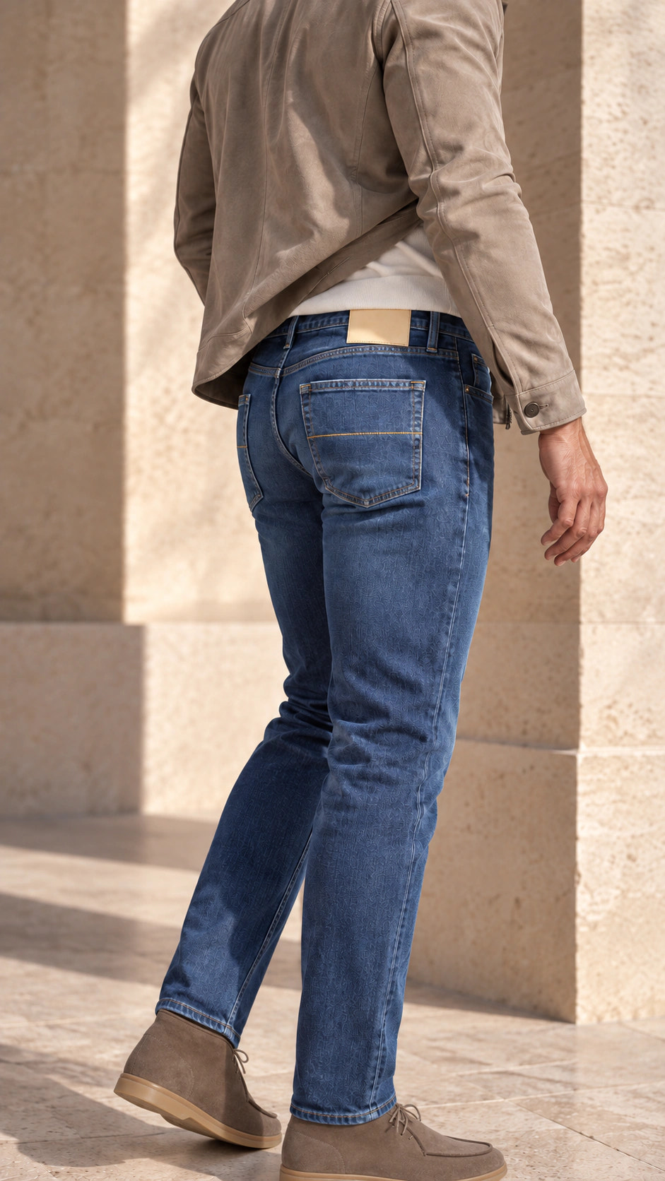 Rear view of the look with bright blue denim and a taupe jacket.