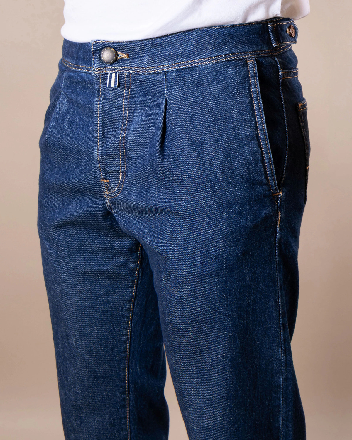 Pleated denim trousers with an angled pocket and a side waist adjuster.