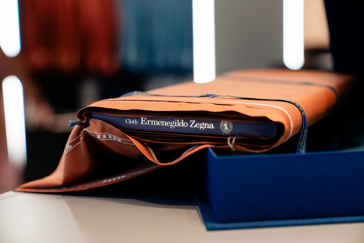Cloth bearing the Ermenegildo Zegna label, resting on the presentation books.