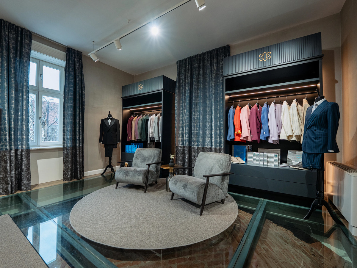 The lounge, with grey armchairs and colourful clothing displays.
