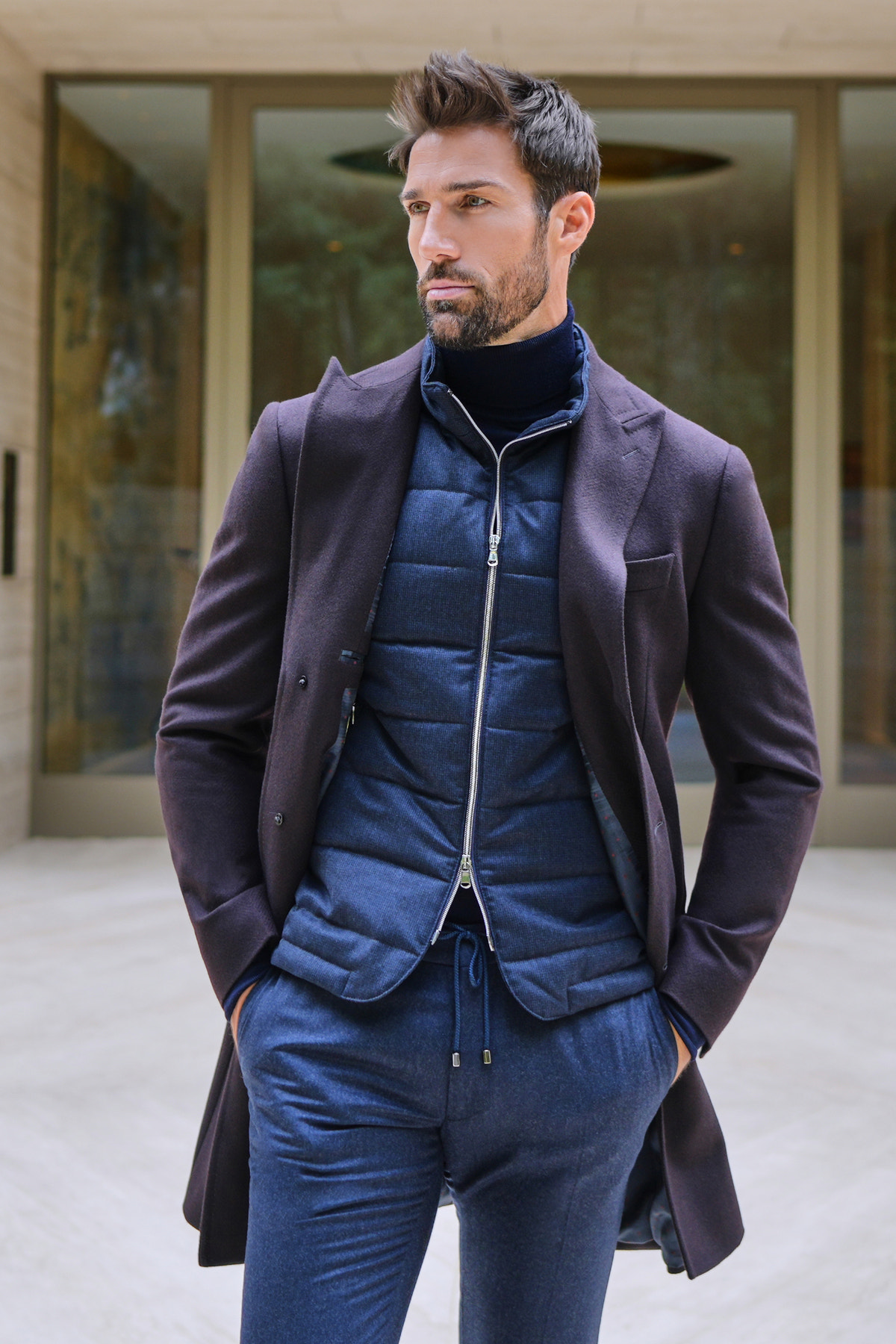 Consiglieri: navy quilted zip-front gilet beneath a dark overcoat