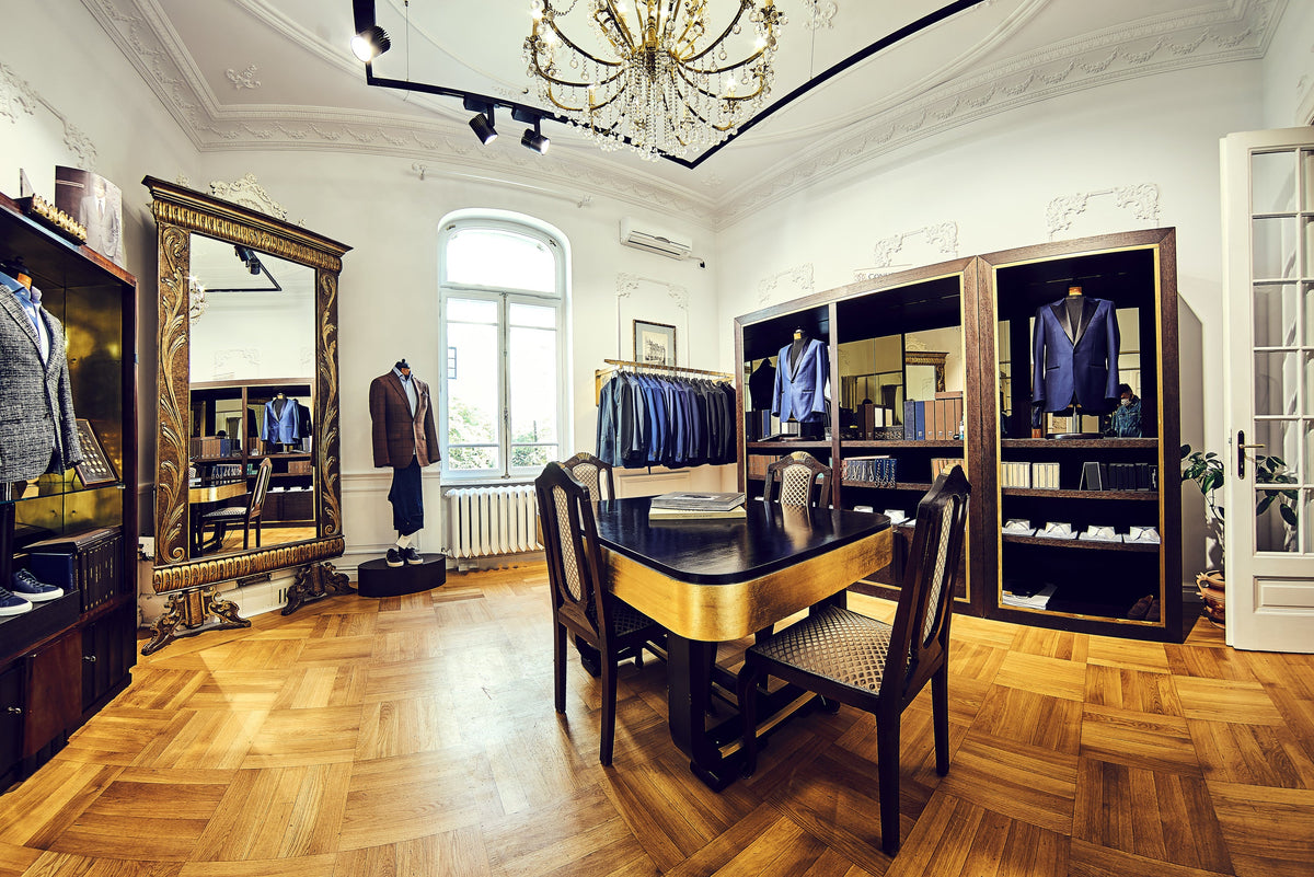 A wooden consultation table surrounded by displayed suits in the Consiglieri showroom