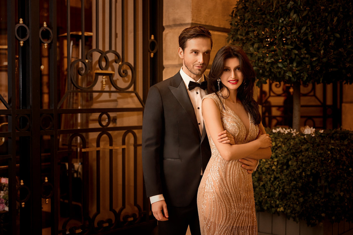Couple in evening attire beside an ornate gate