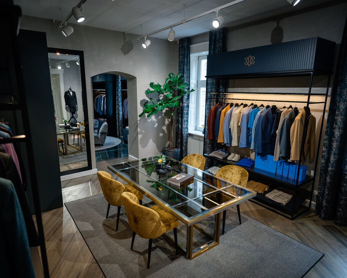 A glass consultation table and mustard chairs beside a selection of jackets in the Consiglieri showroom