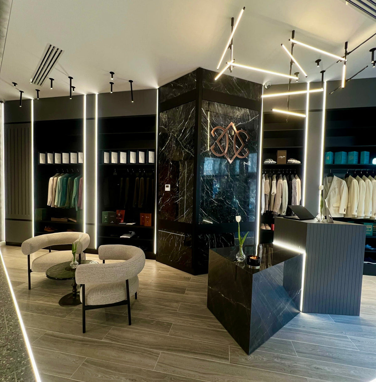 The Consiglieri monogram on a dark panel, with pale armchairs and displayed clothing in the showroom