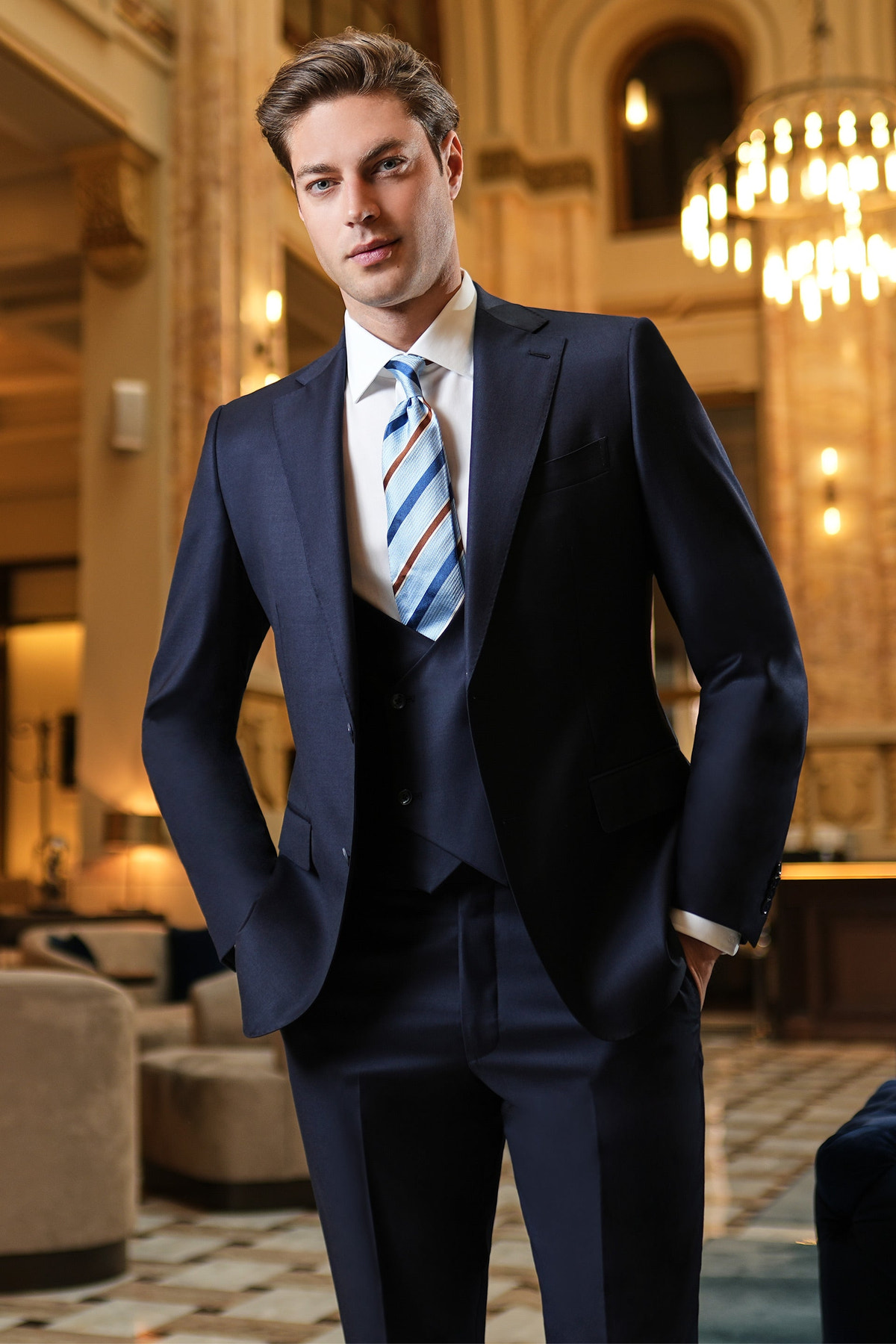 Navy three-piece suit with a striped tie in an elegant interior