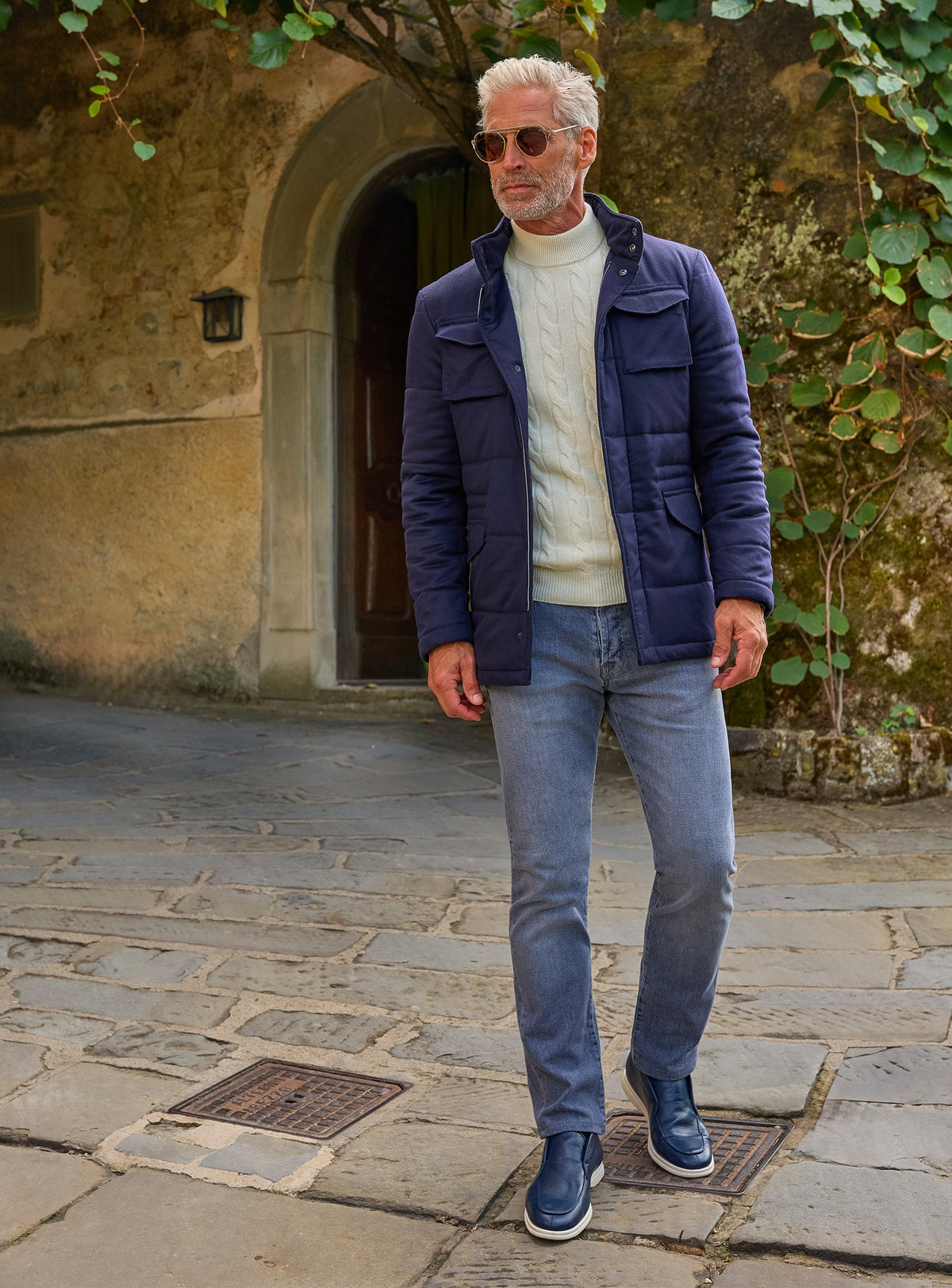 Consiglieri: navy quilted jacket with an ivory cable-knit sweater and blue jeans
