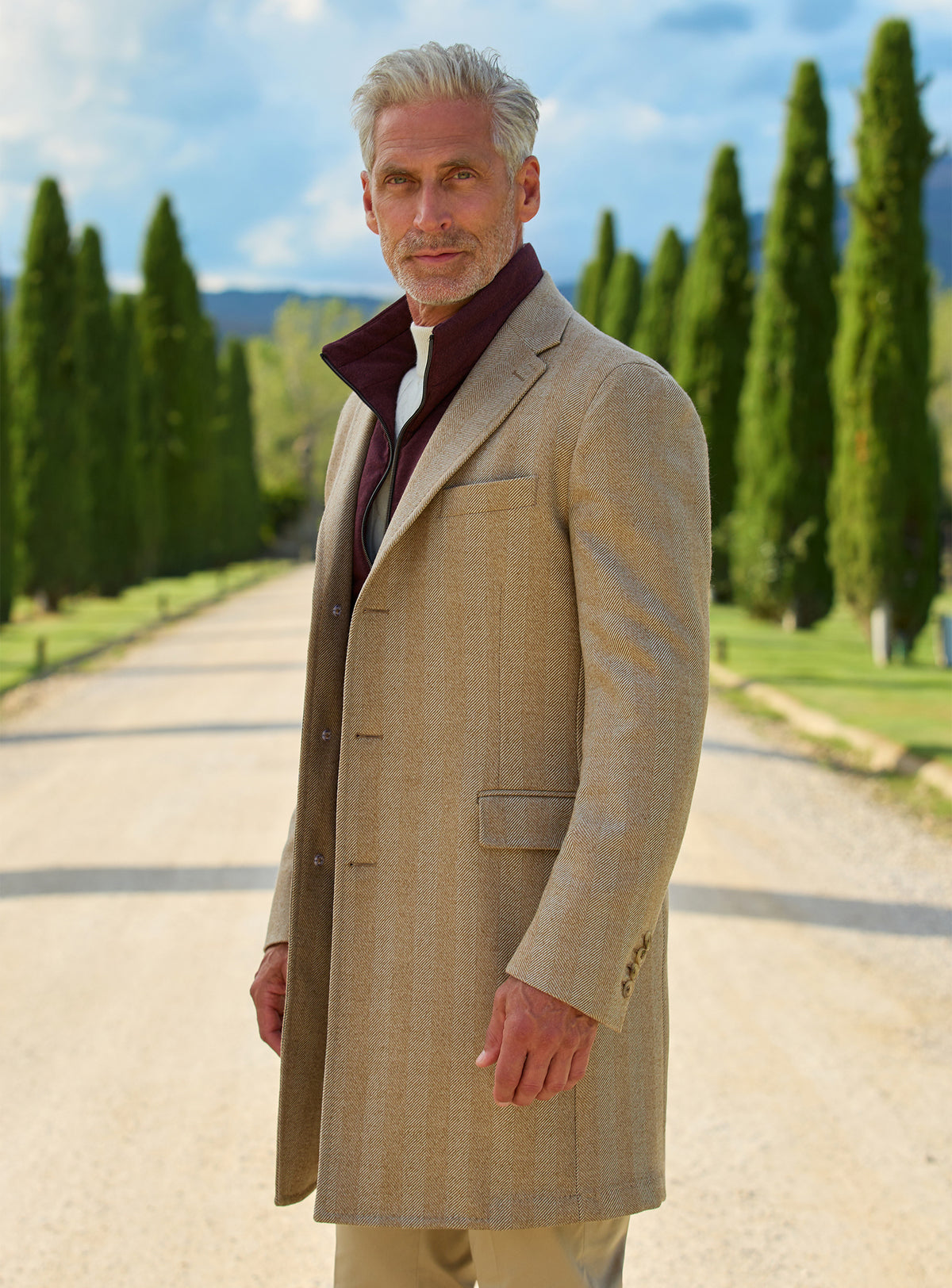 Consiglieri: camel overcoat with a contrasting burgundy collar and cream trousers