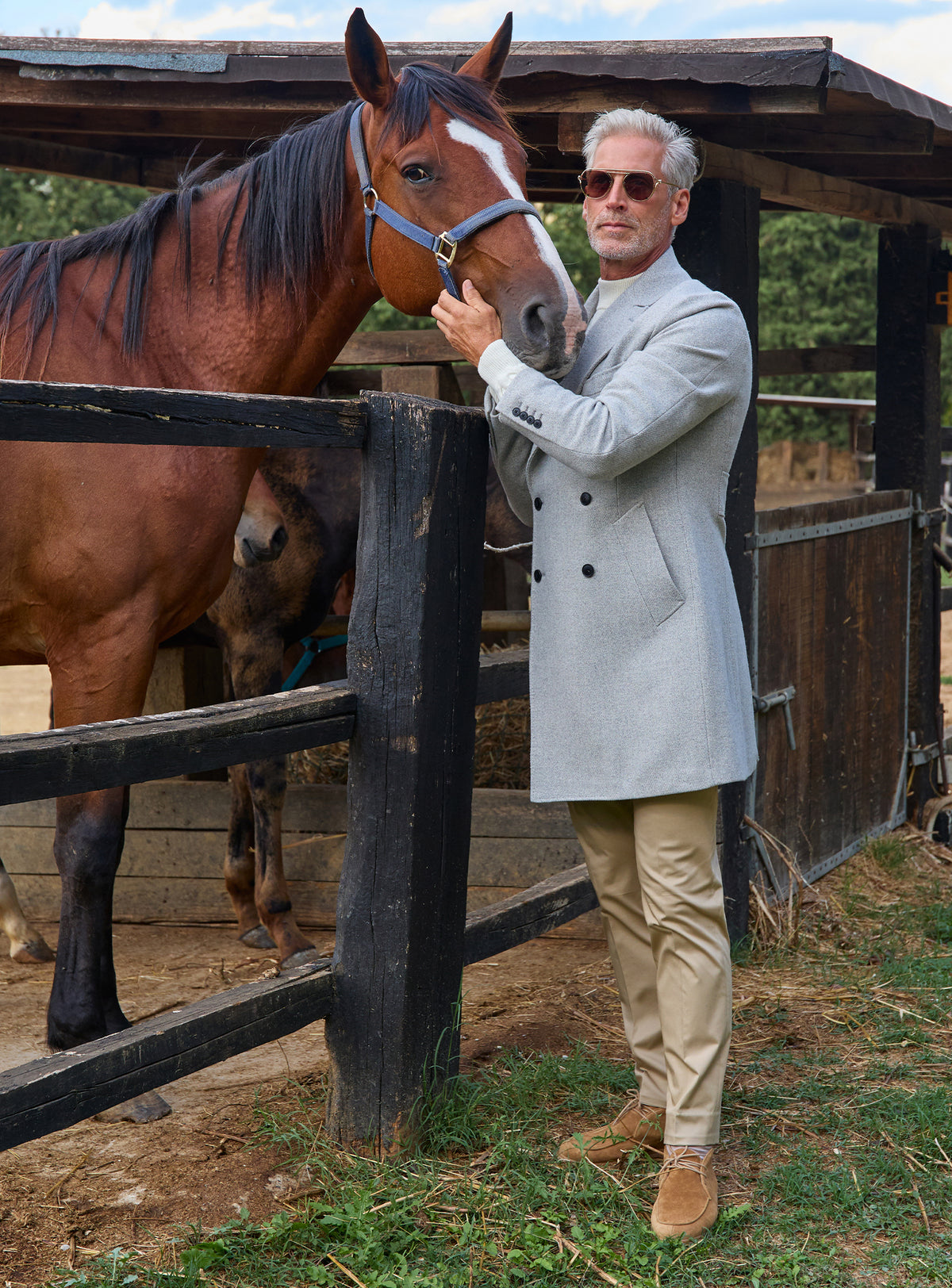 Consiglieri: light grey double-breasted overcoat worn beside a horse