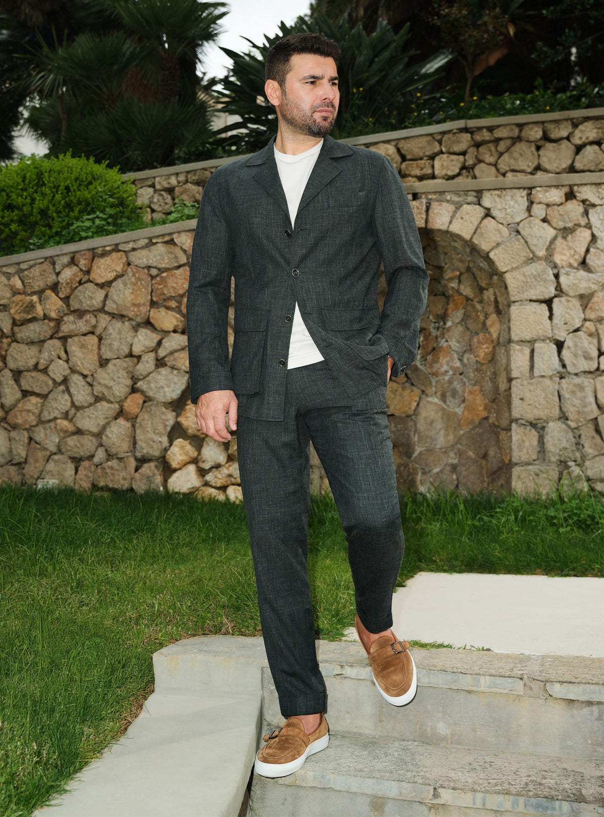 Dark green Consiglieri suit casually styled with a white T-shirt and brown loafers