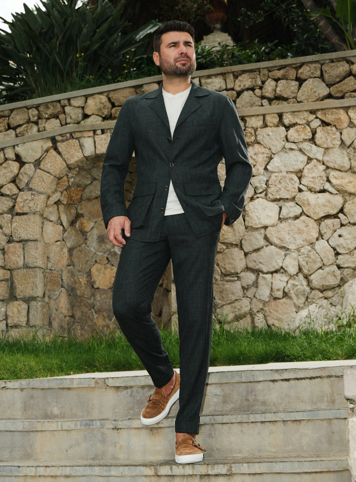 Dark green Consiglieri suit casually styled with a white T-shirt and brown loafers