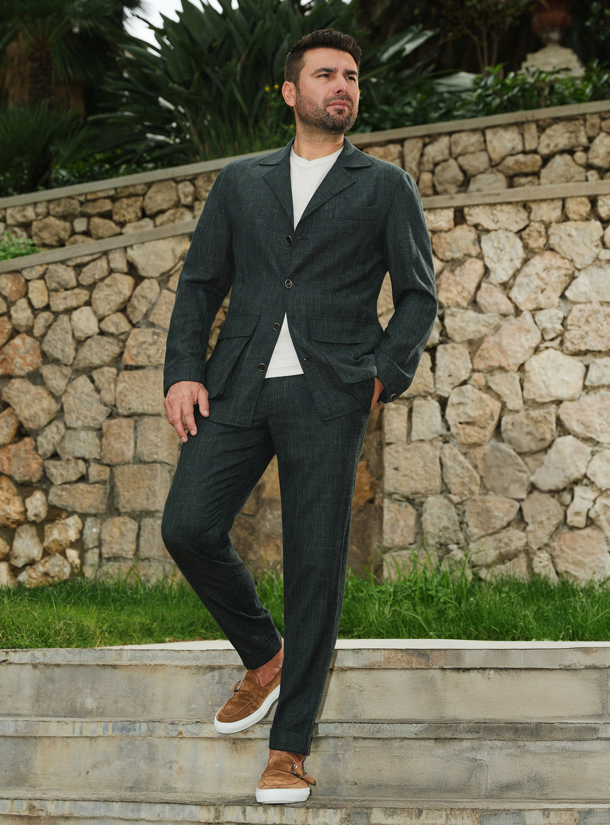 Dark green Consiglieri suit casually styled with a white T-shirt and brown loafers