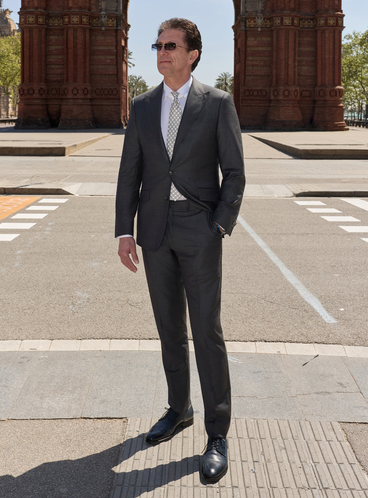 Charcoal Consiglieri suit with notch lapels, a white shirt and light tie