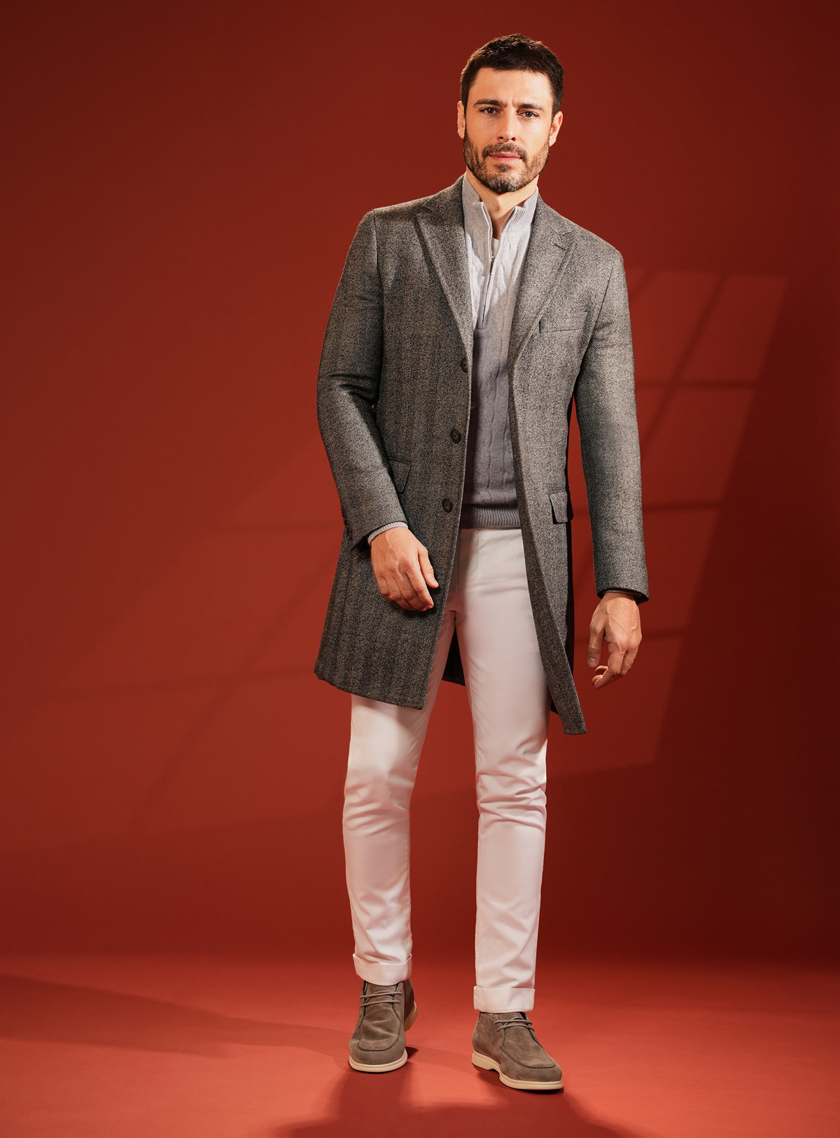 Dark grey Consiglieri overcoat with white trousers and neutral-toned footwear