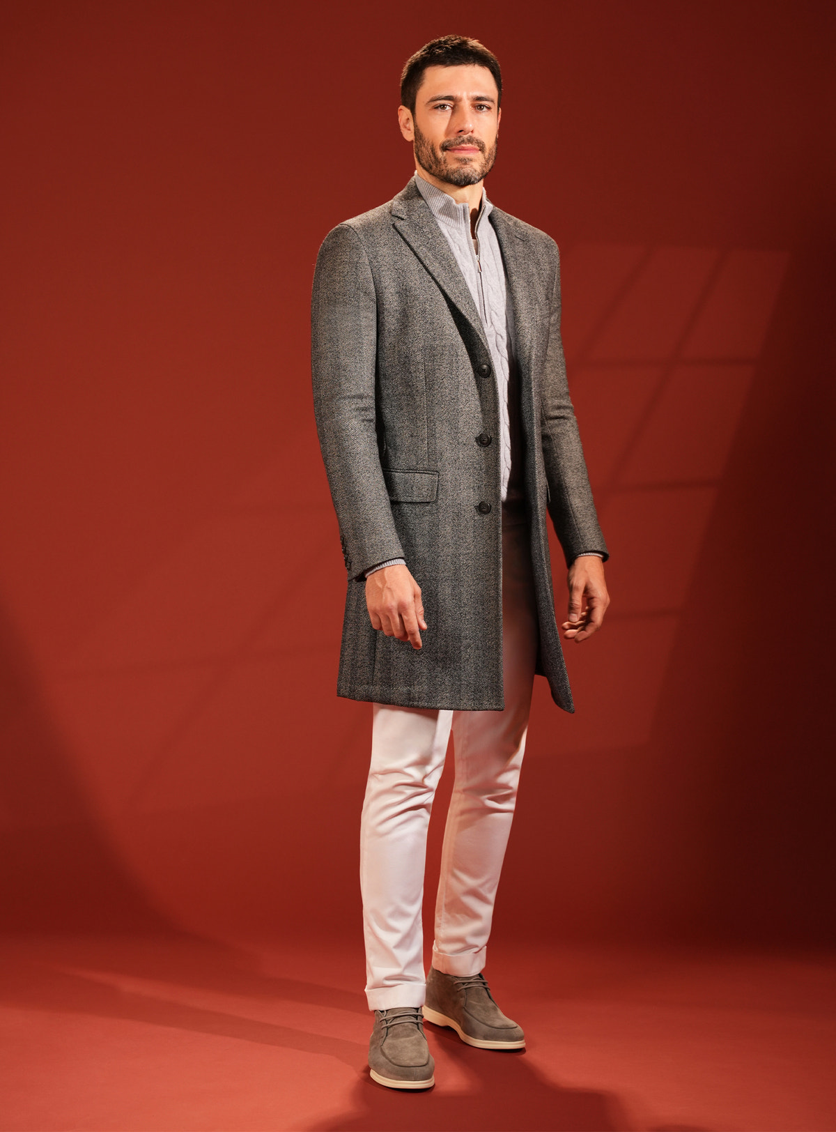 Dark grey Consiglieri overcoat with white trousers and neutral-toned footwear