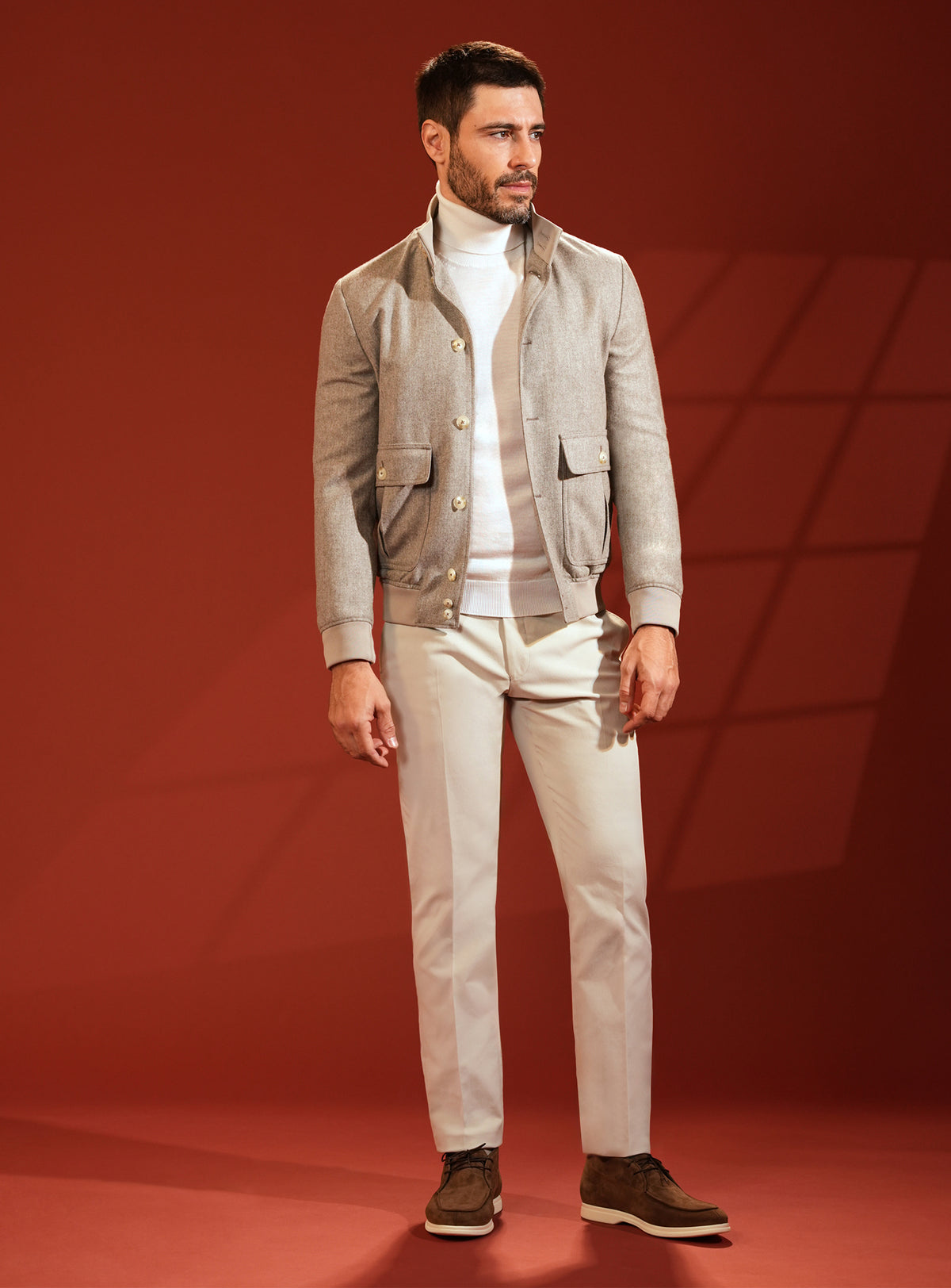 Grey-beige Consiglieri jacket worn with an ivory turtleneck and light trousers