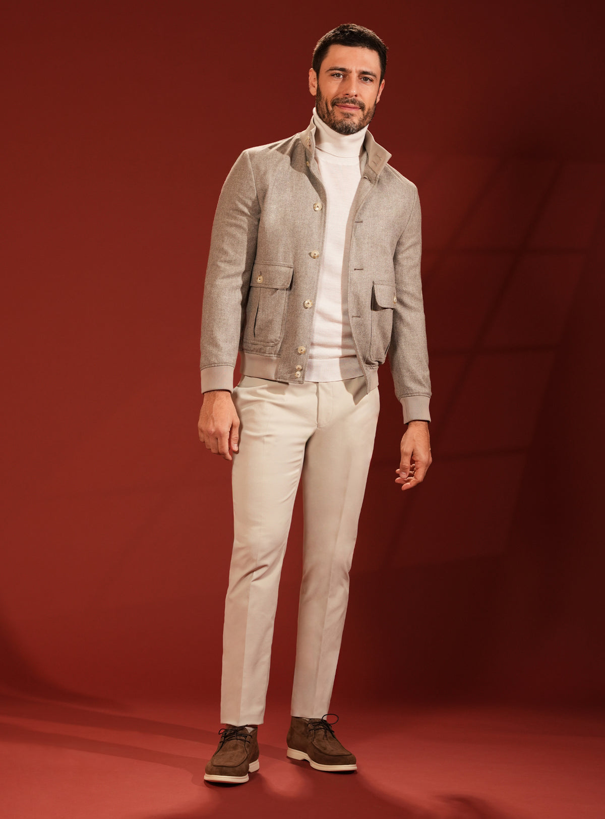 Grey-beige Consiglieri jacket worn with an ivory turtleneck and light trousers