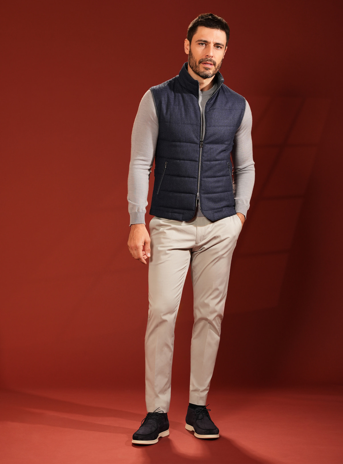 Navy quilted Consiglieri vest with a grey sweater and beige trousers