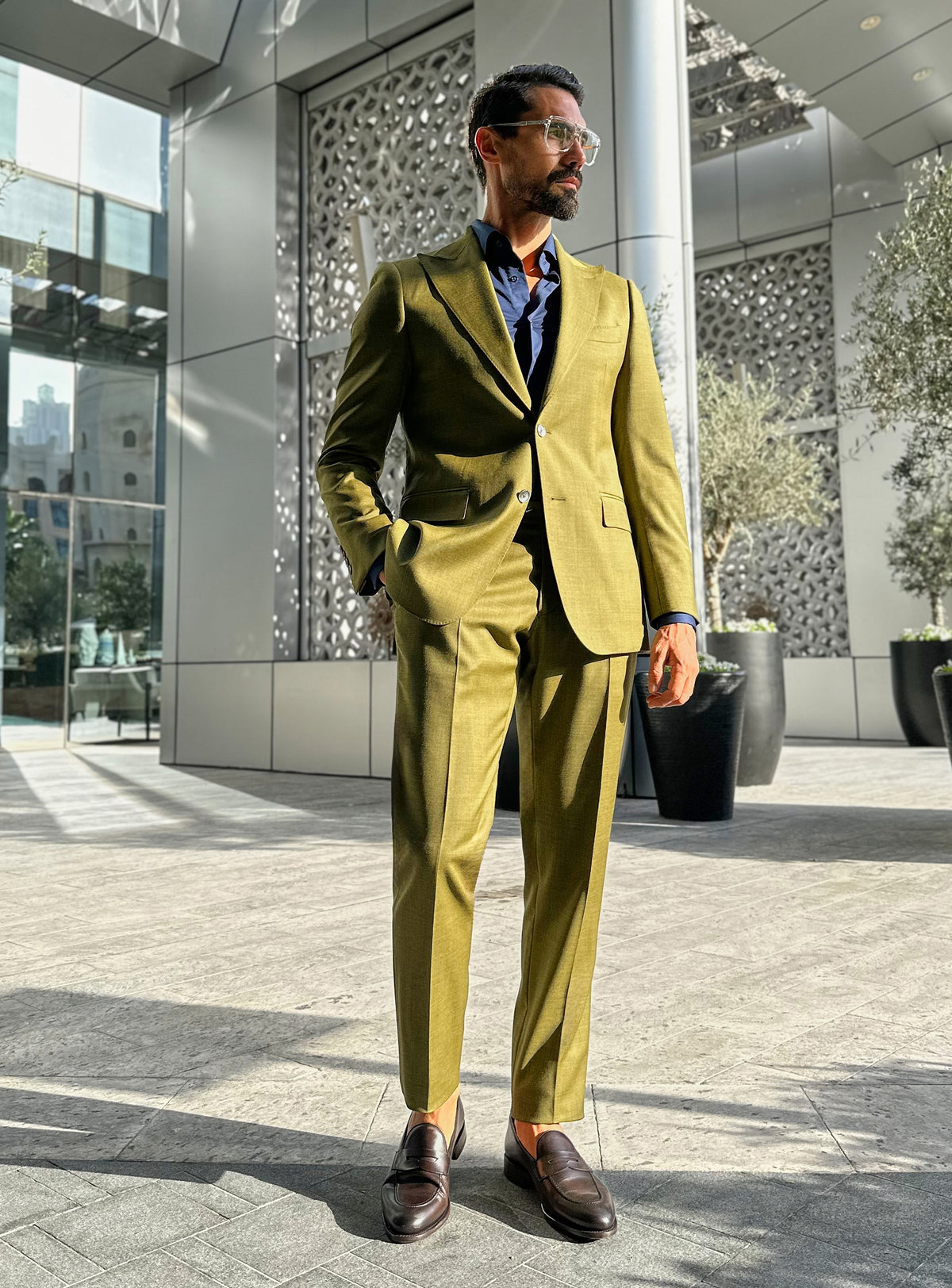 Olive green Consiglieri suit with a dark shirt and brown loafers