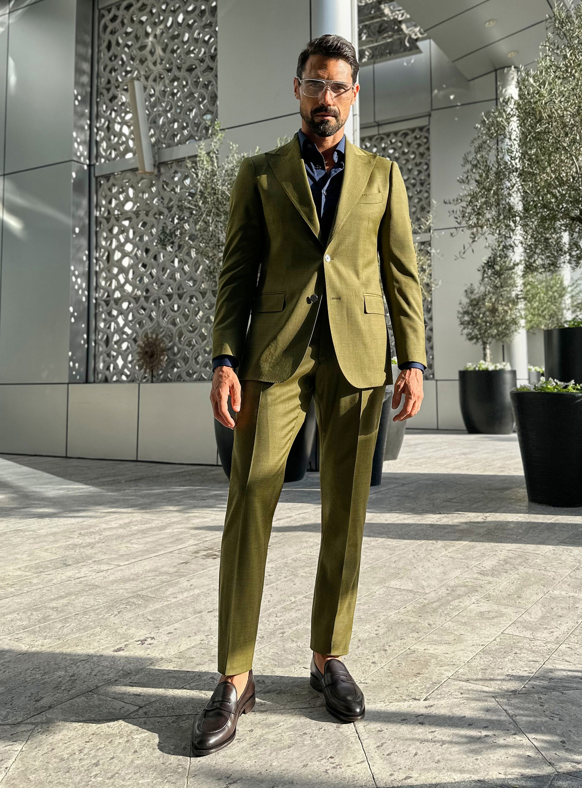 Olive green Consiglieri suit with a dark shirt and brown loafers