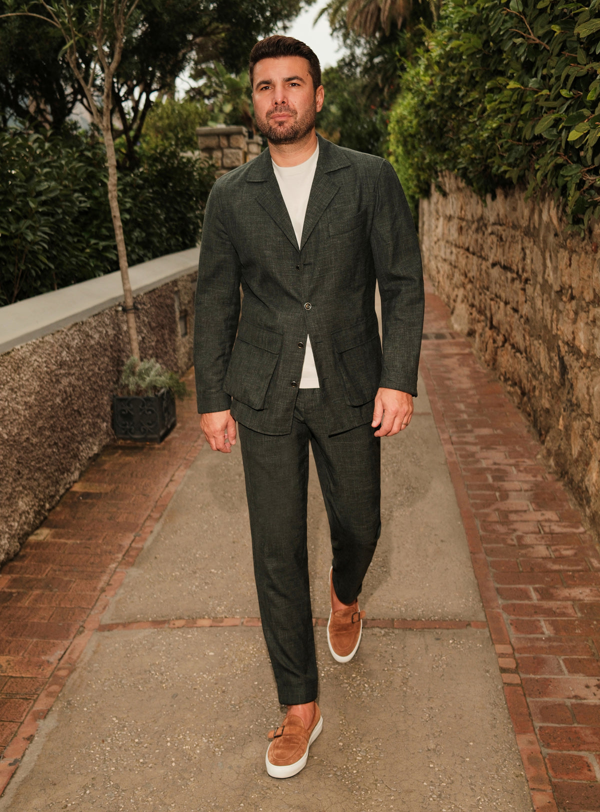 Dark green Consiglieri suit casually styled with a white T-shirt and brown loafers