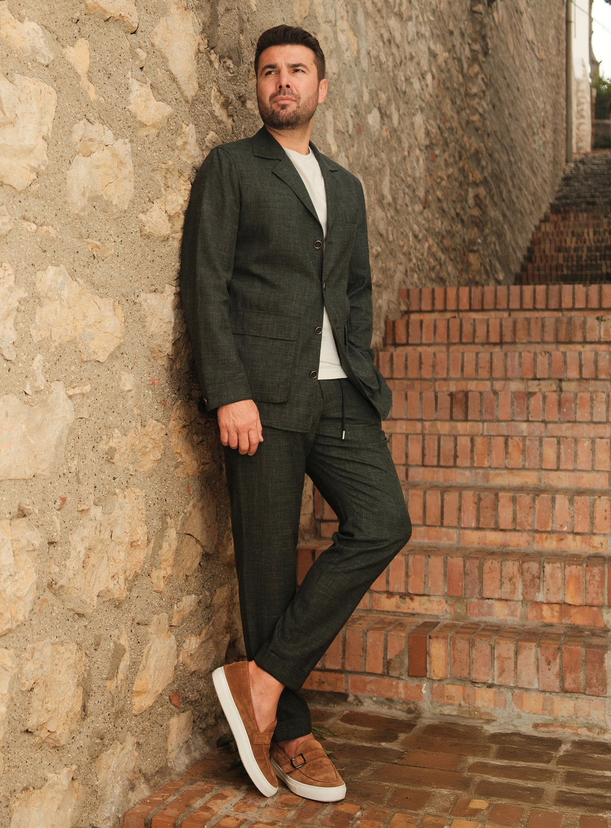 Dark green Consiglieri suit casually styled with a white T-shirt and brown loafers