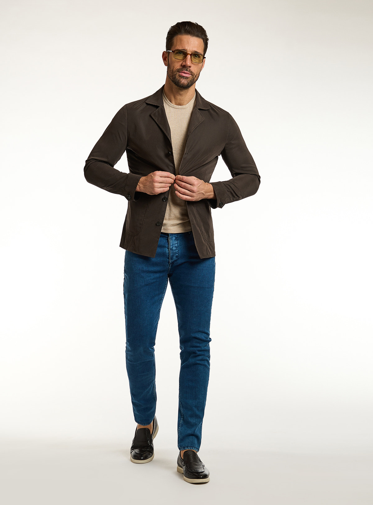 Consiglieri: beige T-shirt beneath a dark brown jacket, with blue jeans