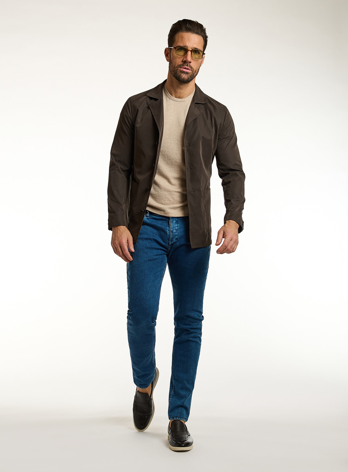 Consiglieri: beige T-shirt beneath a dark brown jacket, with blue jeans
