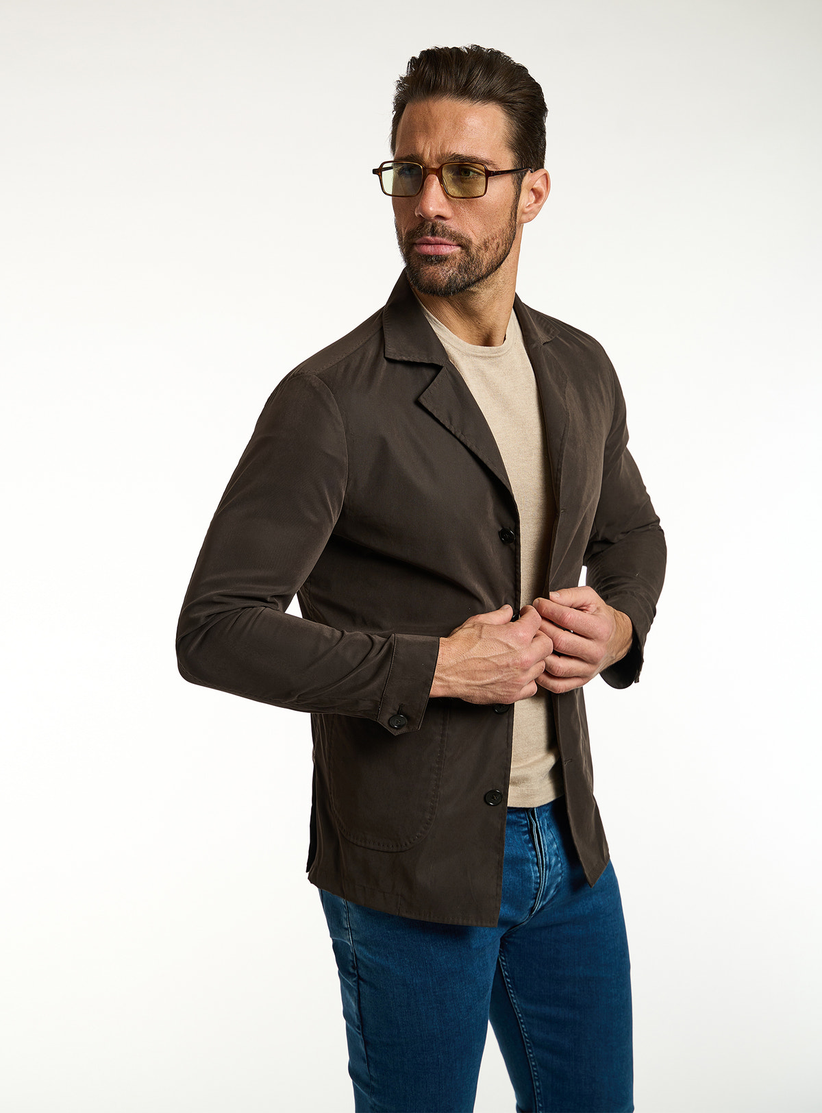 Consiglieri: beige T-shirt beneath a dark brown jacket, with blue jeans