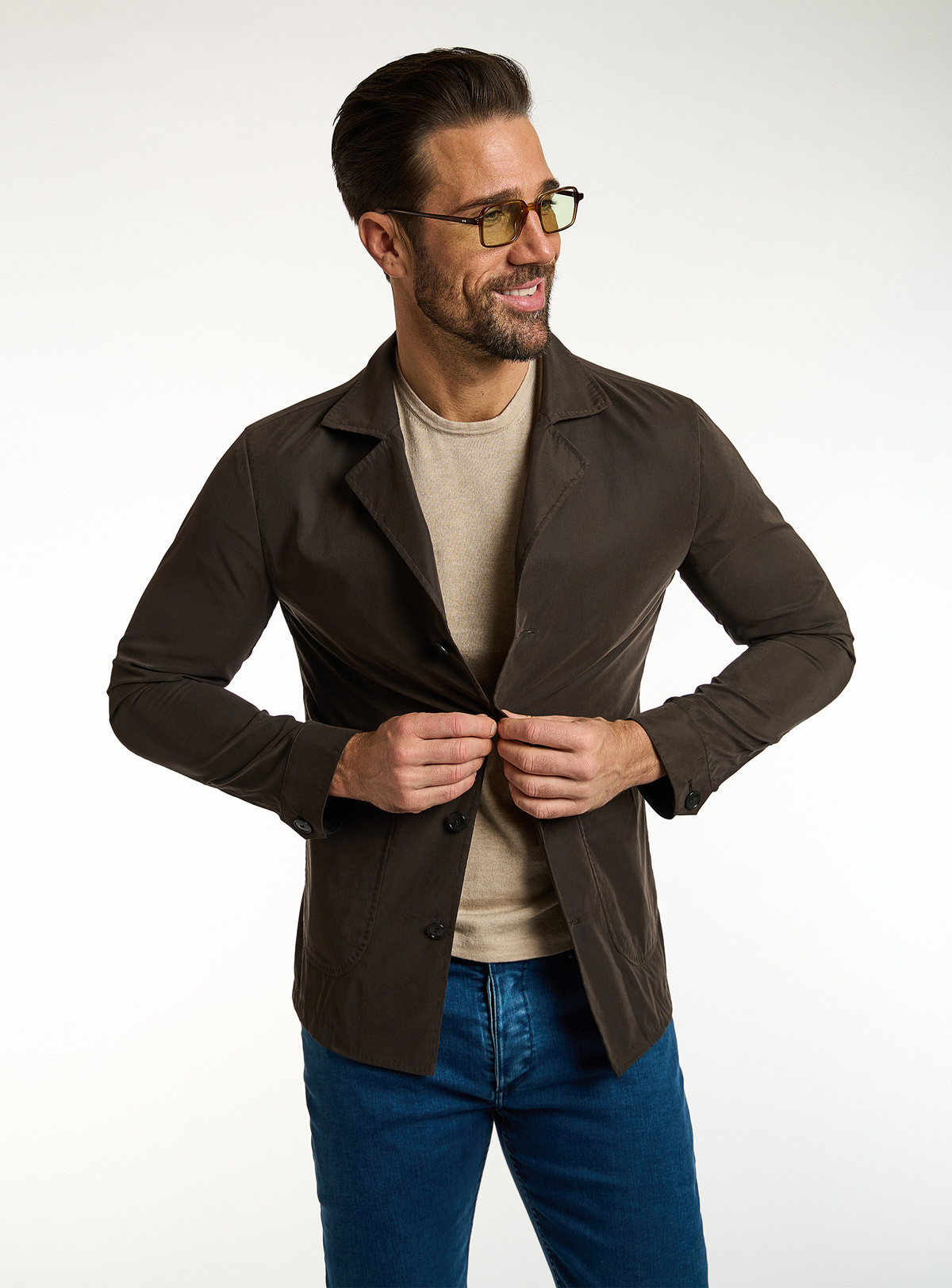 Consiglieri: beige T-shirt beneath a dark brown jacket, with blue jeans