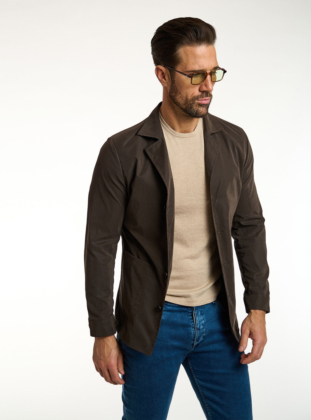 Consiglieri: beige T-shirt beneath a dark brown jacket, with blue jeans
