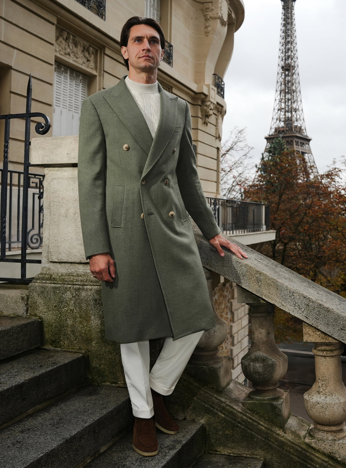 Long olive green Consiglieri overcoat with a light turtleneck and white trousers