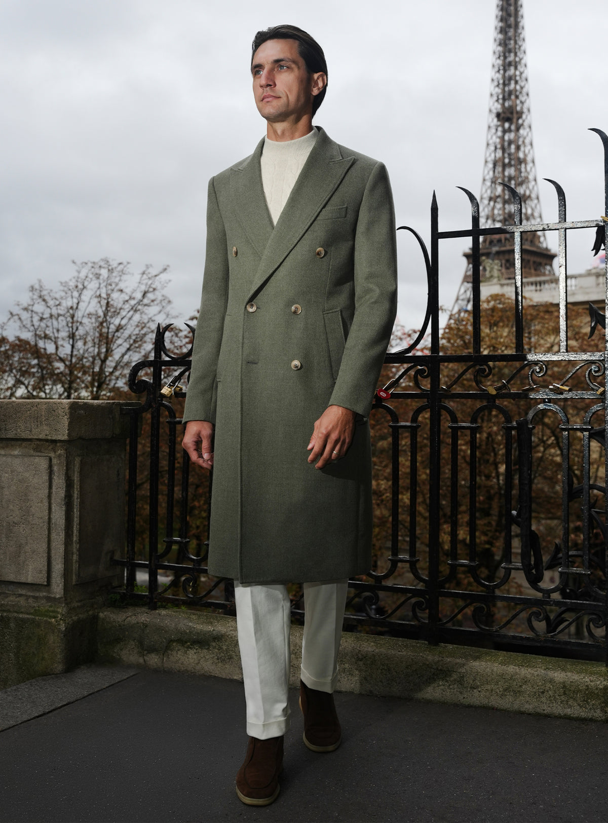 Long olive green Consiglieri overcoat with a light turtleneck and white trousers