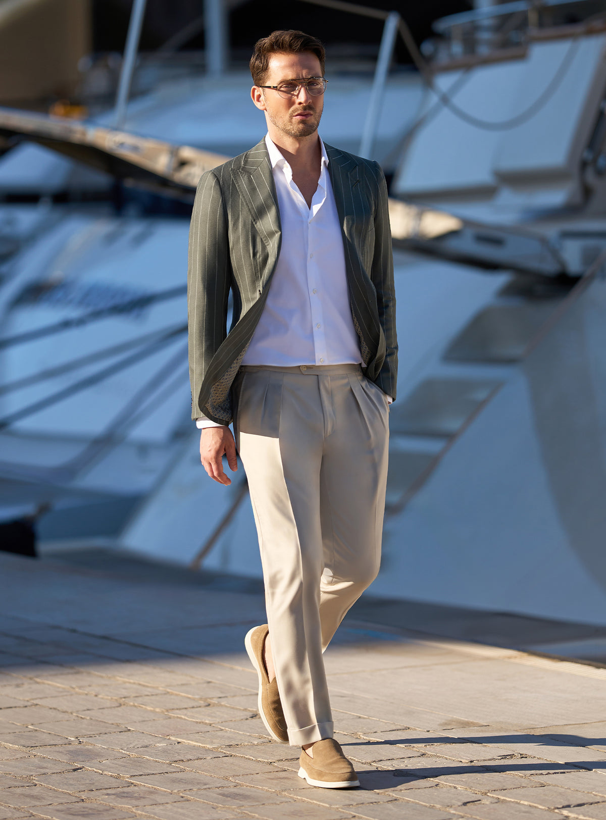 Consiglieri look beside yachts, with a dark green jacket and beige trousers