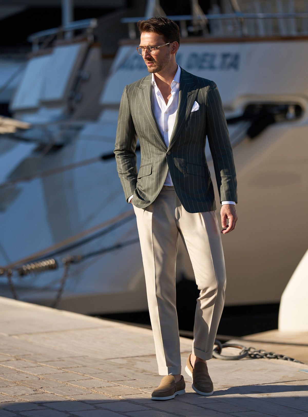 Consiglieri look beside yachts, with a dark green jacket and beige trousers
