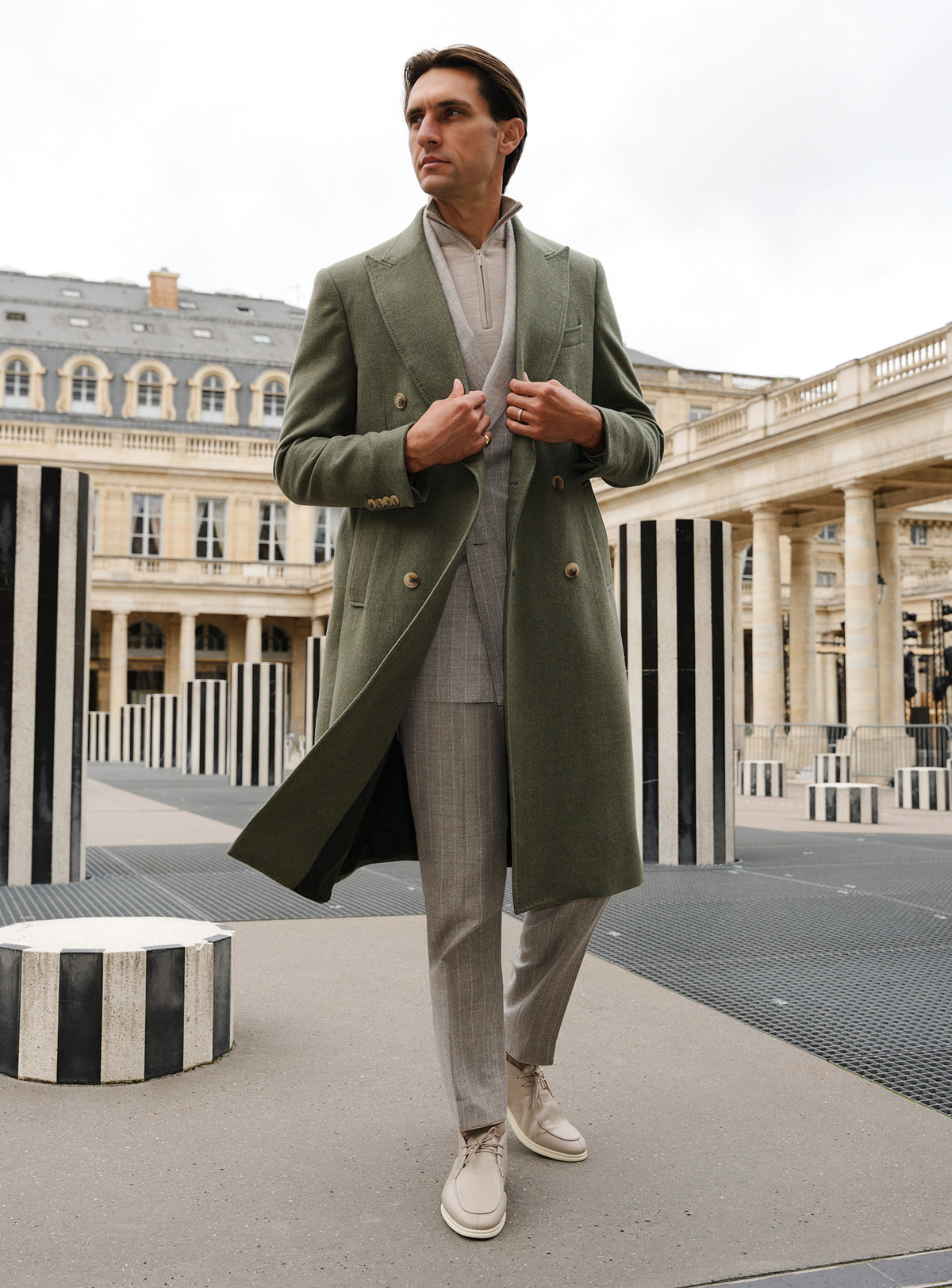 Long olive green Consiglieri overcoat with a double-breasted front and light trousers