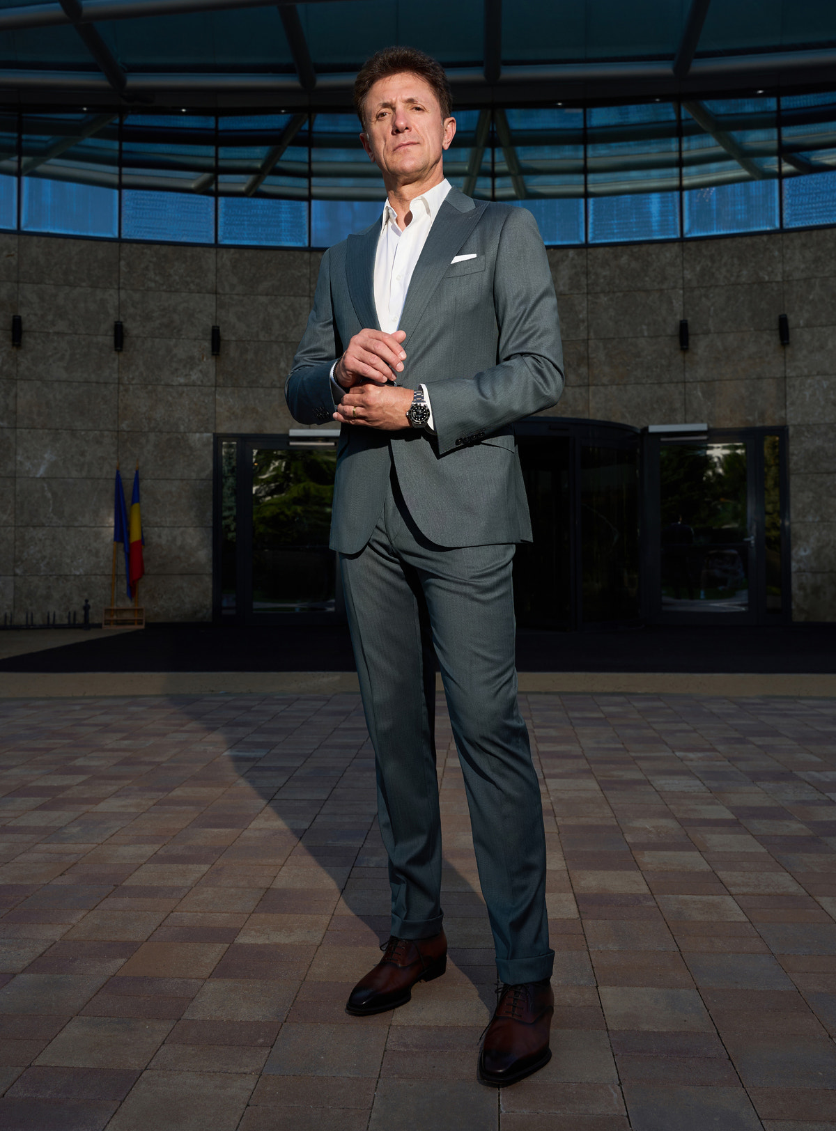 Grey-green Consiglieri suit in a complete look with brown shoes