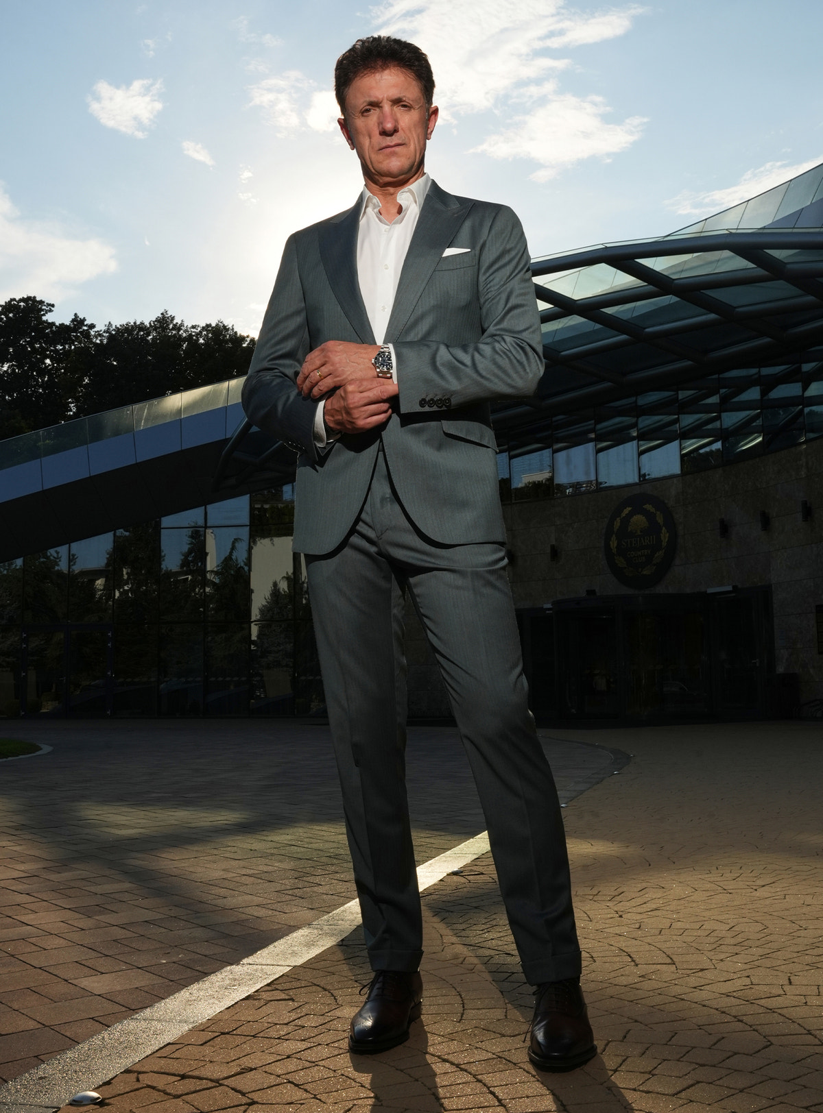 Grey-green Consiglieri suit in a complete look with brown shoes
