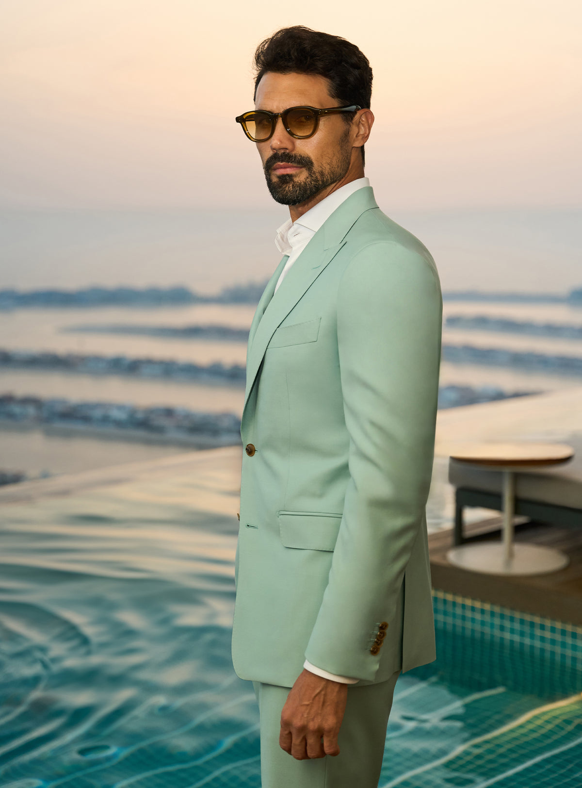 Consiglieri Sapphire Sophistication: mint green suit with a white shirt beside a pool