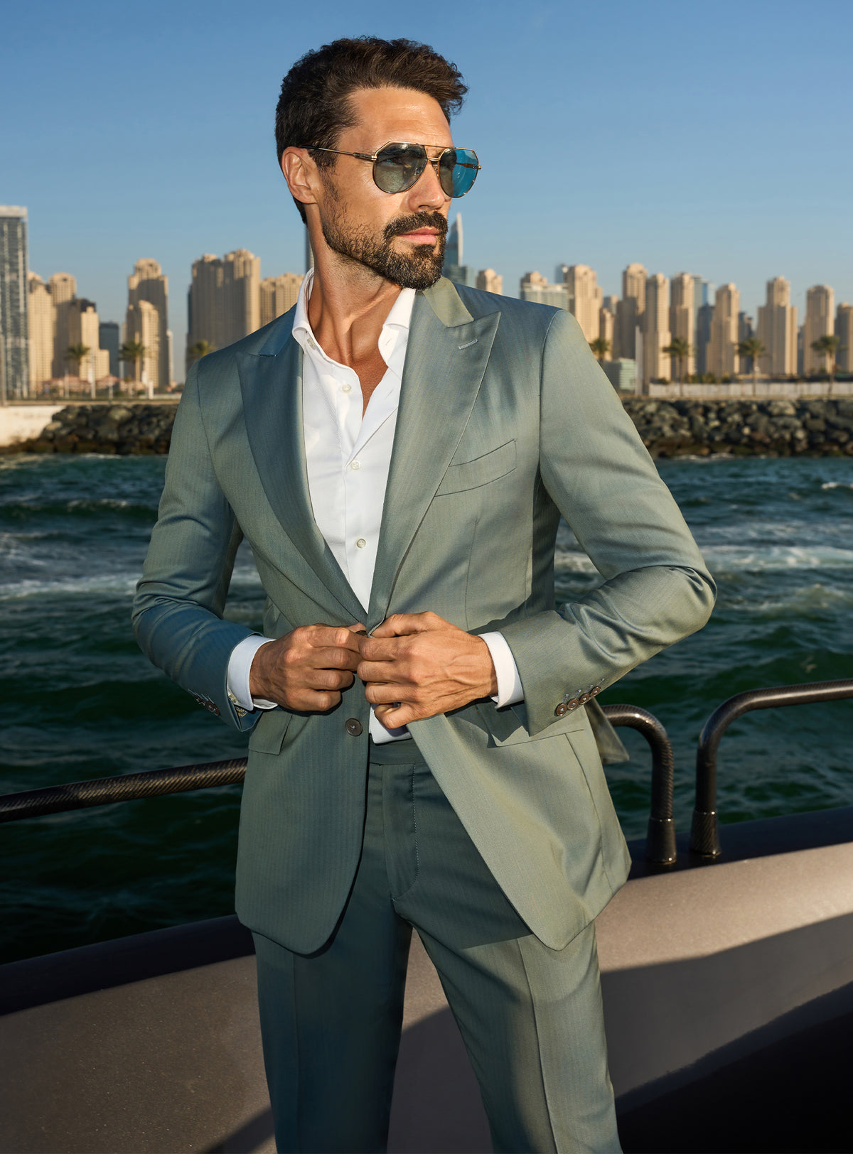 Consiglieri Solaris Essence: sage green suit with a white shirt against a waterfront city backdrop
