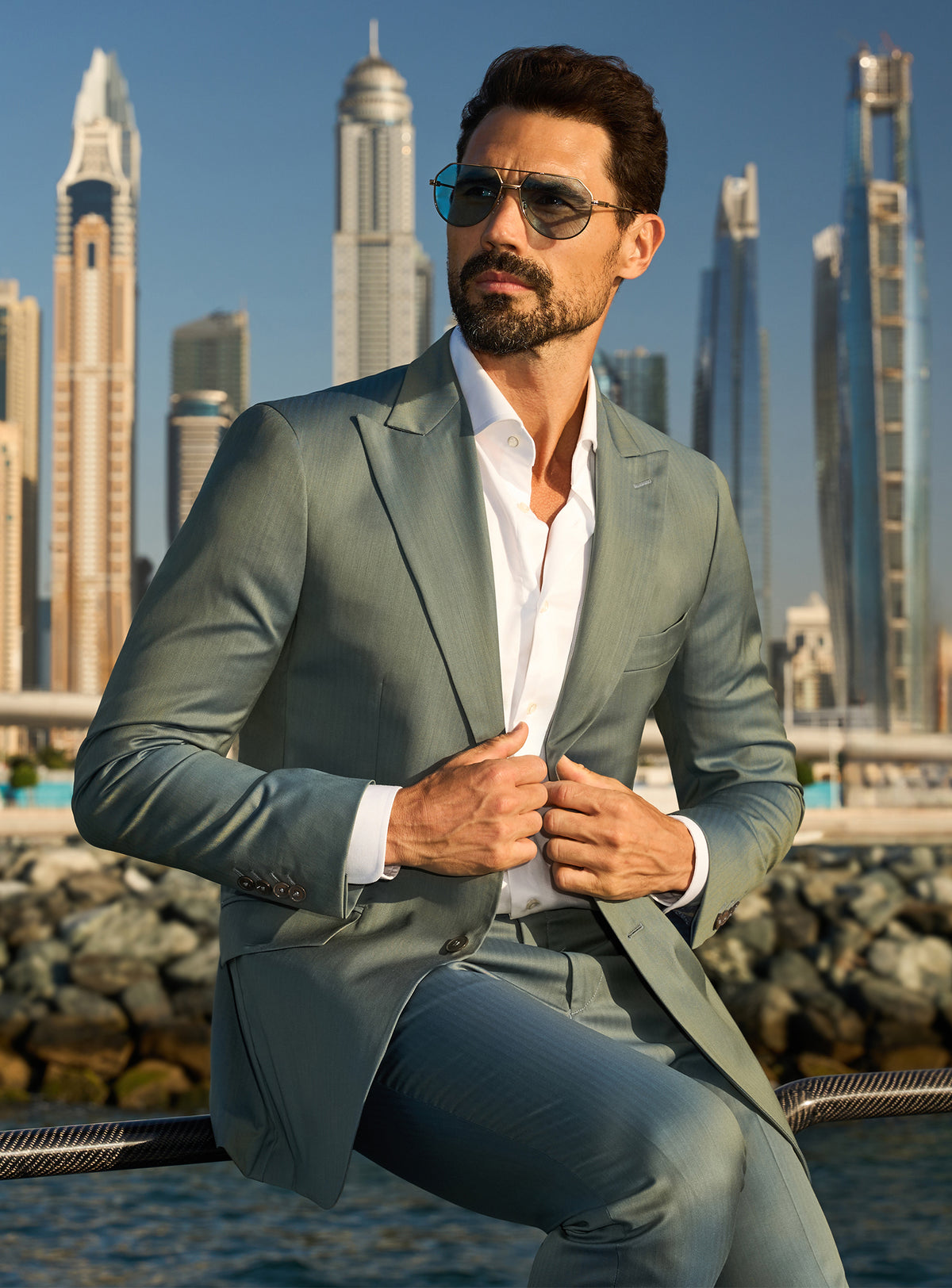 Consiglieri Solaris Essence: sage green suit with a white shirt against a waterfront city backdrop