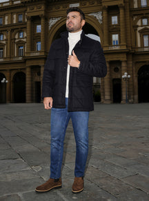 Blue Consiglieri jeans with a navy jacket, white turtleneck and brown loafers