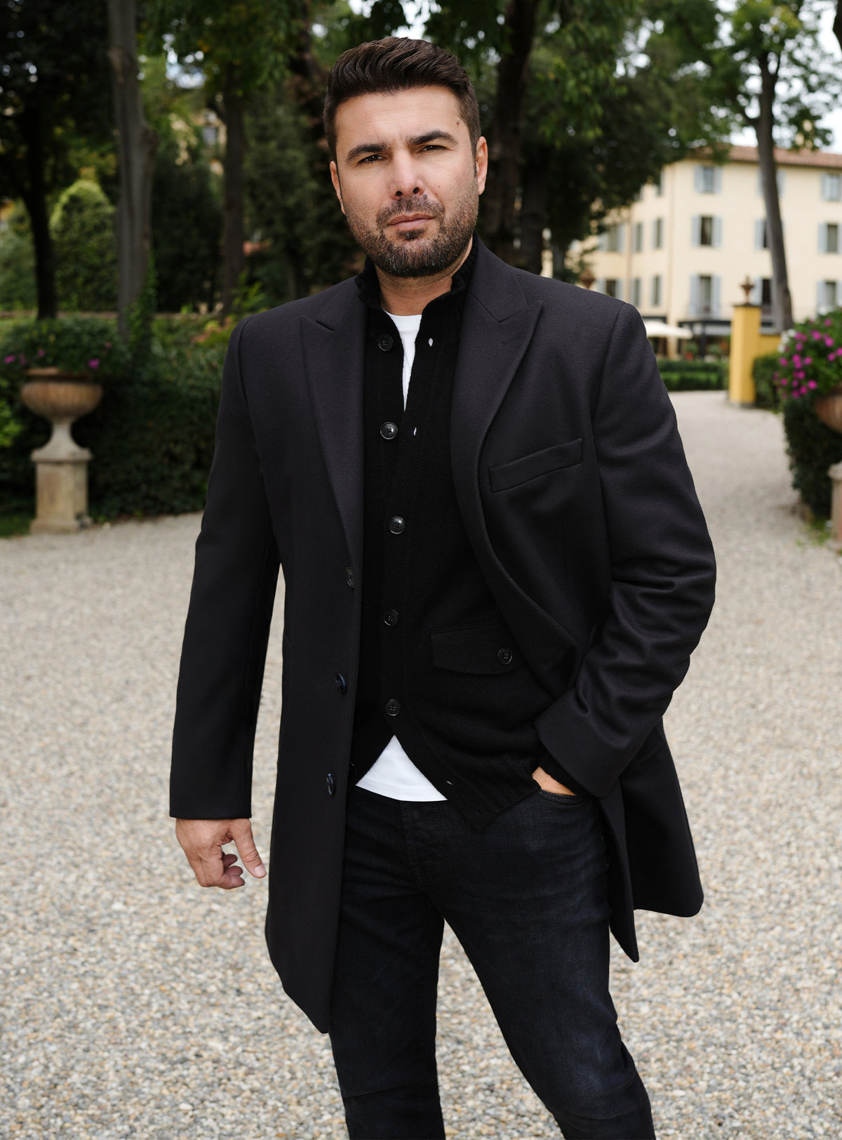 Black Consiglieri overcoat with notch lapels, styled with a black cardigan and trousers