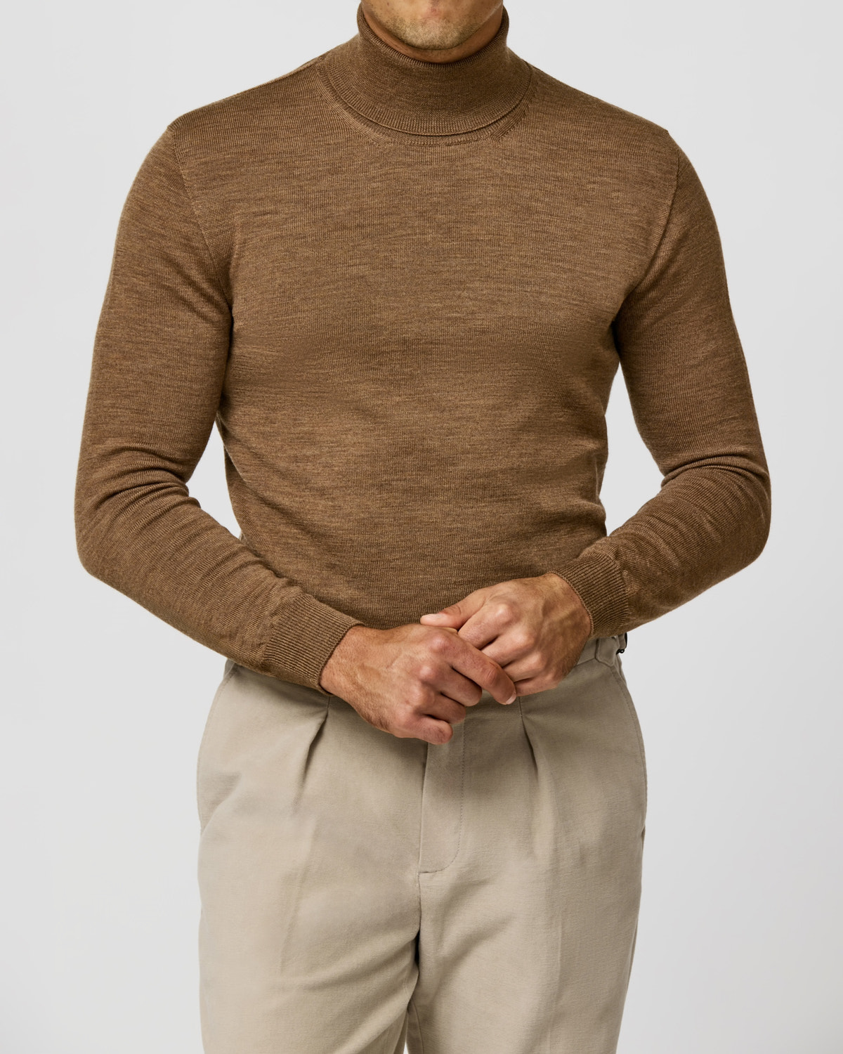 Brown Consiglieri turtleneck worn with pleated beige trousers