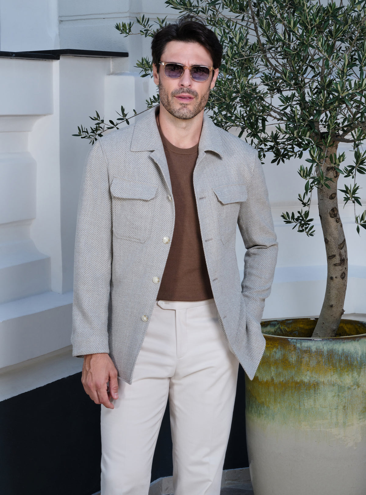Light beige Consiglieri jacket with flap pockets, a brown sweater and white trousers